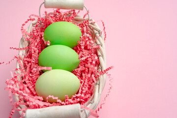 Painted Easter eggs in decorative nest on pink background