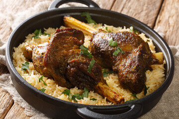 Popular Yemeni baked lamb shank served with basmati rice close-up in a frying pan on the table. horizontal
