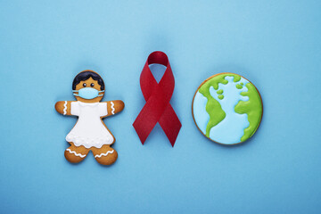 red ribbon and gingerbread girl and planet earth on blue background. world day of fight against cancer