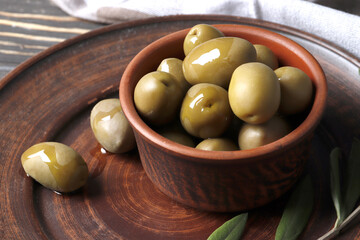 Composition of green olives, olive oil, marinade on a wooden background close up