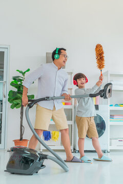 Father and son is singing and wearing headphone while doing house cleaning together, with joy and happiness, for Family togetherness cocnept.