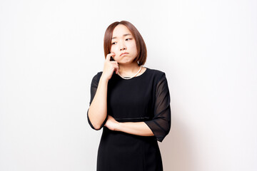 悩んでいるジェスチャーをする喪服を着た女性