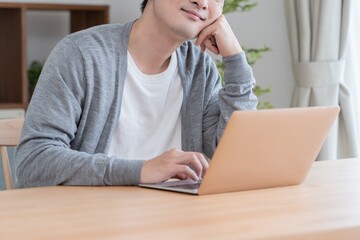 自宅でパソコン作業をするアジア人男性