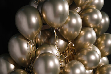 Celebration and party golden christmas baloons with golden ribbons isolated on black background....