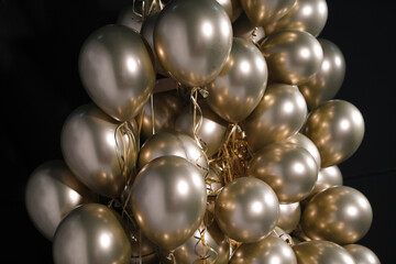 Celebration and party golden christmas baloons with golden ribbons isolated on black background. Event decoration. New year eve. Christmas party.