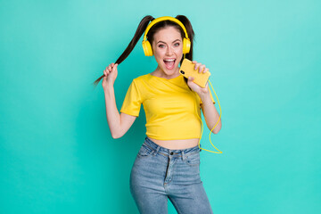 Portrait of pretty impressed brunette girl sing in telephone wear headphones t-shirt isolated on cyan color background