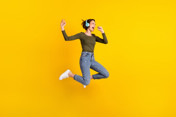 Fototapeta na wymiar Full body photo of girl jump listen music on wireless headset sing song use hand as mic isolated over shine color background