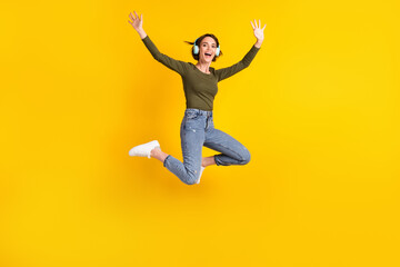 Fototapeta na wymiar Full body photo of girl jump listen music wireless headset wear sweater isolated on bright yellow color background