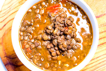 Bowl of lentils on a wooden tray and white background