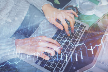 Fototapeta premium Double exposure of woman hands typing on computer and forex chart hologram drawing. Stock market invest concept.