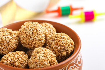 Til Gul OR Sweet Sesame seed ball or Laddu with Fikri for Indian festival Makar Sankranti over white background