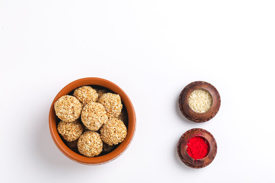 Til Gul OR Sweet Sesame seed ball or Laddu with Fikri for Indian festival Makar Sankranti over white background