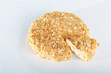 Festive puff pastry cake with custard. On a light background. Sprinkled with crumbs. Birthday, holidays, sweets.