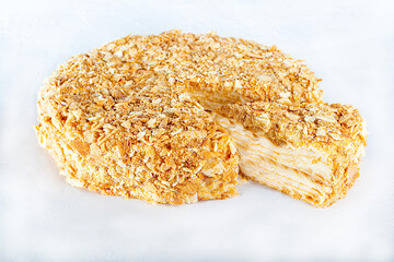 Festive puff pastry cake with custard. On a light background. Sprinkled with crumbs. Birthday, holidays, sweets.