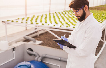 Male scientist making notes on clipboard