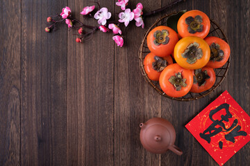 Top view of fresh sweet persimmons with leaves on wooden table background for Chinese lunar new year