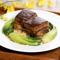 ong Po Pork meat in a blue plate with broccoli with red background.