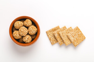 Til chikki and sesame seed ball on white background is an Indian sweet dish made with jaggery and sesame seeds.