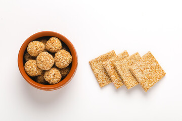 Til chikki and sesame seed ball on white background is an Indian sweet dish made with jaggery and...