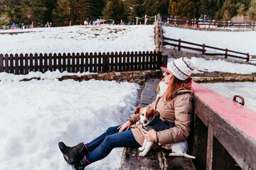 woman and cute jack russell dog enjoying outdoors at the mountain with snow. winter season