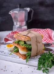 sandwich of French toast and lettuce leaves and boiled egg, a vegetarian food wrapped in paper