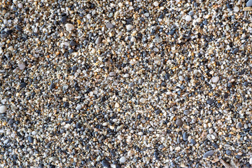 Closeup background of pebble stones of sand on a sea shore.