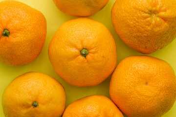 Ripe tangerines on a yellow background. Tangerine fruit with peel. Citrus fruits with vitamins for immunity and health. Top view, flat lay