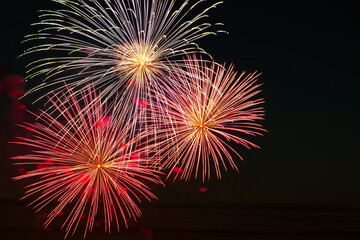 Festive fireworks in the sky for a holiday. Bright multi-colored salute on a black background. Place for text.