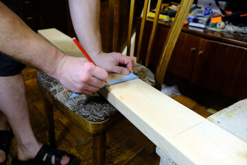 Carpenter marks a board with a pencil