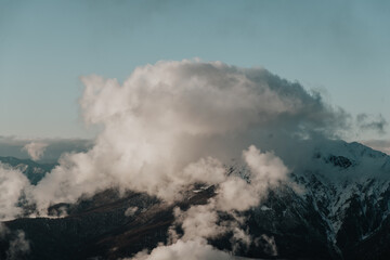 Fototapeta na wymiar Rosa Khutor. Large cloud over snow-capped mountains.