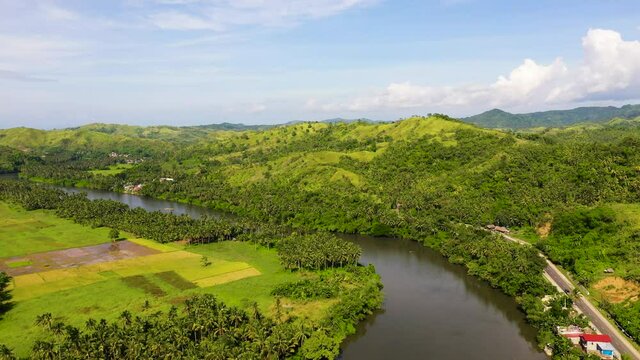 Countryside on a large tropical island. Small village on the green hills by the river. Tropical landscape in sunny weather. Village by the river. The nature of the Philippines, Samar