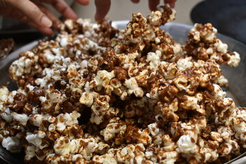 making caramel popcorn with hands in vessel at home