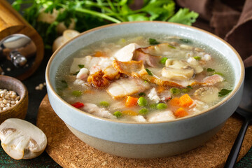Healthy eating. Homemade hearty soup with cereals, bacon and mushrooms on a dark stone background.