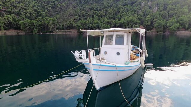 Greek traditional wooden fishing boat in the harbour at dusk