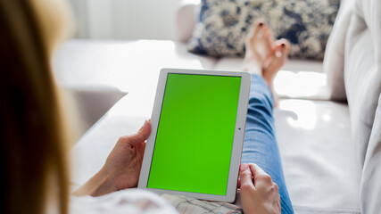 young woman is relaxing on comfortable couch and using tablet at home