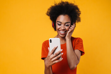 Joyful african american girl in wireless headphones using mobile phone