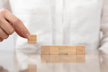 Female hand arranging wood block stacking as step stair. Ladder career path concept for business growth success process
