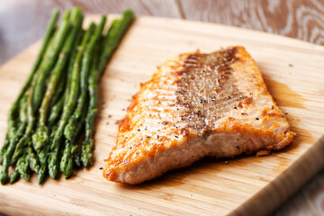 Salmon Fillet with Asparagus ready to eat on a cutting board.
