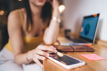 Selective focus on modern smartphone device used by unrecognizable female freelancer checking received text email or app notification, skilled woman browsing website on digital cellular technology