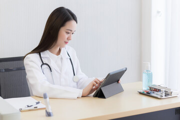 Coronavirus protection concept. Serious professional doctor wearing white coat and stethoscope holding modern touchscreen gadget using digital tablet computer at work.