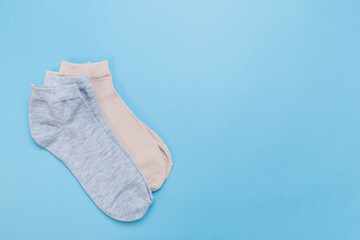 two pairs of multicolored new socks stacked on a blue background. top view.