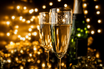 Two glasses and bottle of champagne with bokeh lights in background. New Year's Eve celebration.