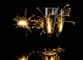 Two glasses of champagne with sparklers in background. New Year's Eve celebration party.