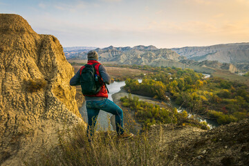 Naklejka premium Back side of Backpacker standing on the hilland looking to rocky landscape of Vashlovani nature reserve