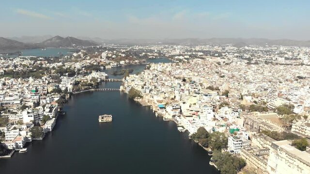 Mohan Mandir Temple in the middle of Lake Pichola Canal amidst the old city in Udaipur, Rajasthan, India - Aerial Fly-over shot
