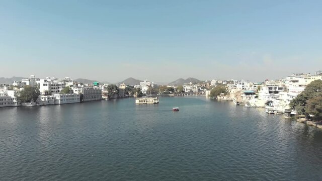 Overview of Pichola Lake to the Mohan Mandir Temple in Udaipur, in Rajasthan, India - Aerial Low-angle Fly-over shot
