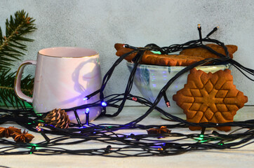 New Year's atmosphere, mood and coziness, warming winter drink tea, cookies in the form of snowflakes and Christmas lights lifestyle at home