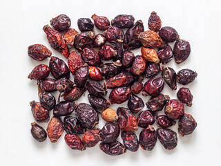 Handful of shriveled and dried rosehip berries on a white background