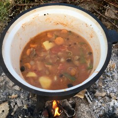 Preparing boar stew on an open fire in sunny day.