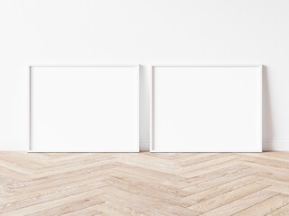 Two blank horizontally oriented rectangular exhibition backgrounds with thin white border standing on wooden parquet floor leaning on white wall. 3D Illustration.